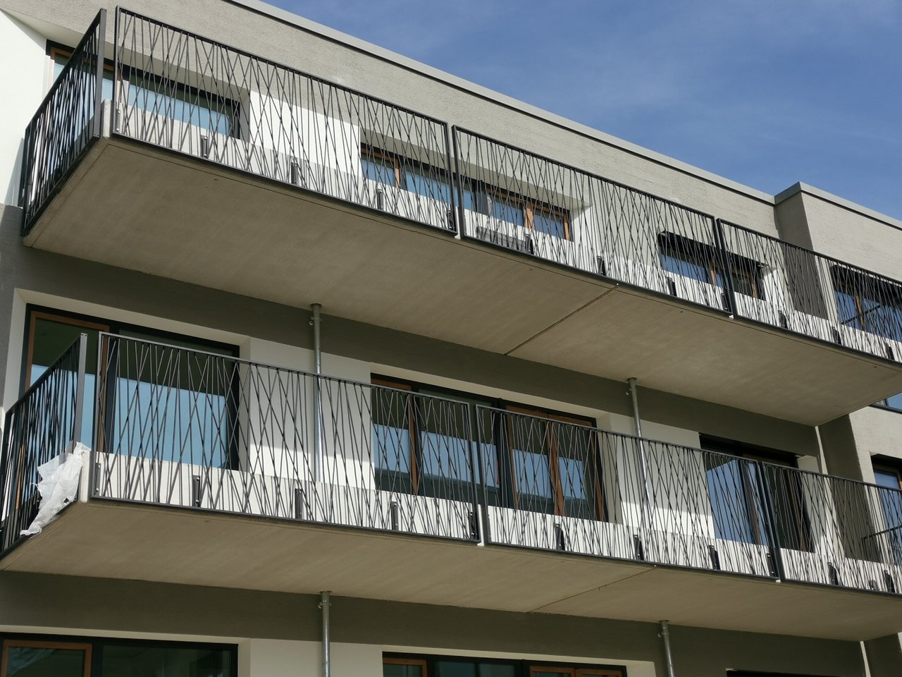 Sanierter Anbaubalkon mit Metallgeländer an einem Mehrfamilienhaus